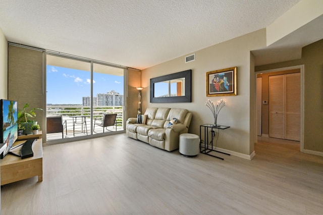 living area with a city view, wood finished floors, visible vents, and expansive windows