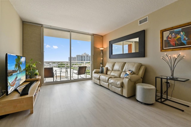 living area with visible vents, floor to ceiling windows, a city view, and wood finished floors