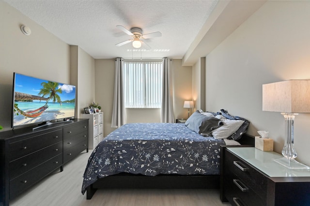 bedroom featuring ceiling fan, a textured ceiling, and light wood-style floors