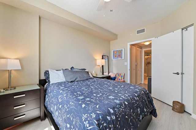 bedroom featuring a textured ceiling, light wood-style floors, visible vents, and ceiling fan