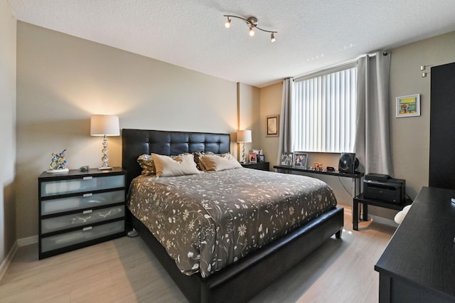 bedroom featuring wood finished floors, baseboards, and a textured ceiling