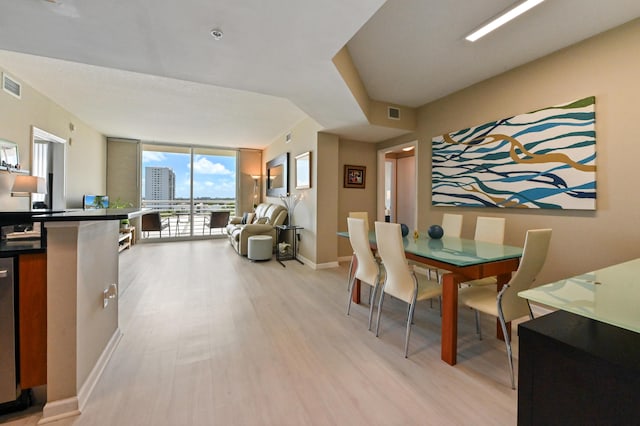 dining room with light wood finished floors, visible vents, floor to ceiling windows, and baseboards