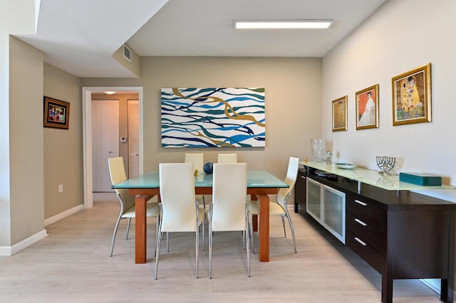 dining room with light wood-type flooring, visible vents, and baseboards