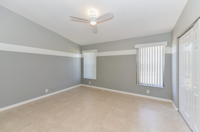 empty room with vaulted ceiling, a ceiling fan, baseboards, and a textured ceiling