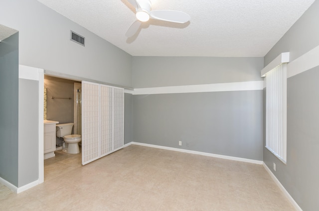 unfurnished bedroom featuring visible vents, ensuite bathroom, a textured ceiling, baseboards, and ceiling fan