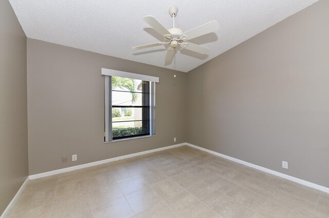 spare room with a ceiling fan, baseboards, lofted ceiling, light tile patterned flooring, and a textured ceiling