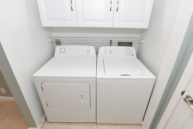 clothes washing area with light tile patterned floors, cabinet space, baseboards, and washing machine and clothes dryer