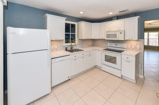 kitchen featuring a sink, visible vents, white appliances, and light countertops