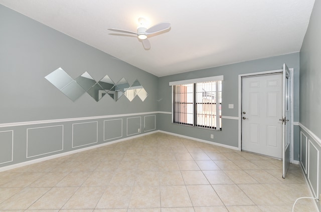 empty room featuring light tile patterned flooring, a decorative wall, and a ceiling fan