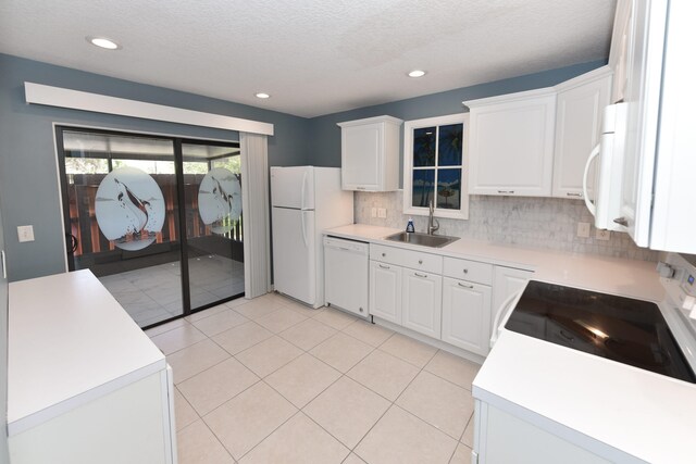 kitchen with a sink, backsplash, white cabinetry, white appliances, and light countertops