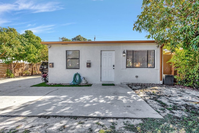 view of front facade featuring stucco siding, a patio, and fence