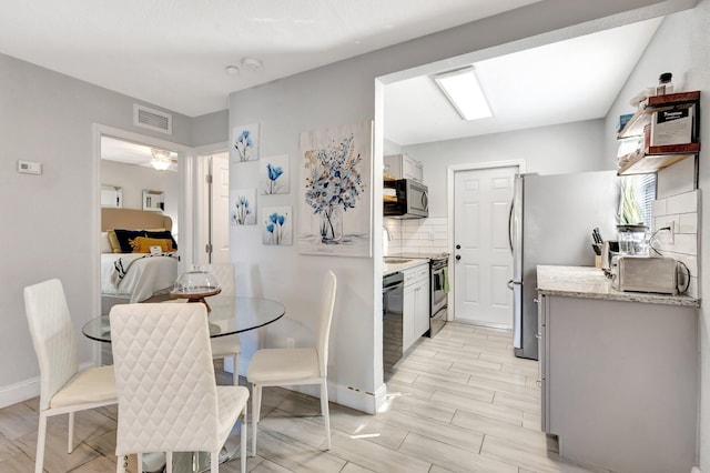 kitchen featuring visible vents, appliances with stainless steel finishes, wood tiled floor, and decorative backsplash