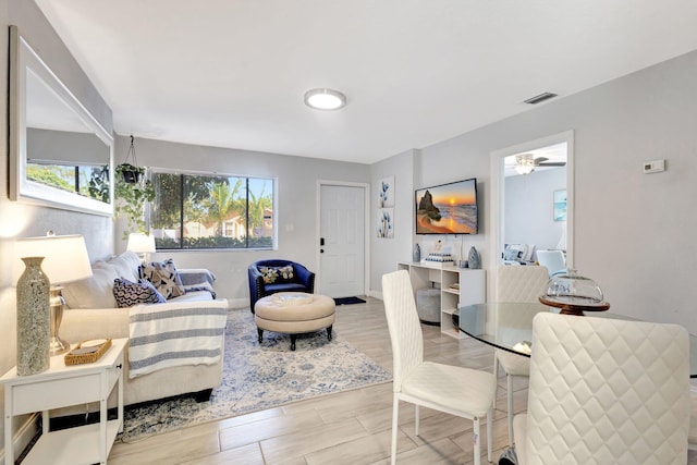 living area with baseboards, visible vents, and wood finish floors