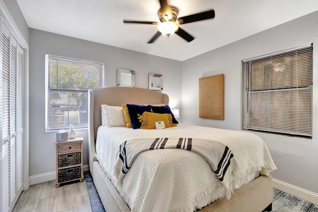 bedroom with a closet, light wood-style flooring, a ceiling fan, and baseboards