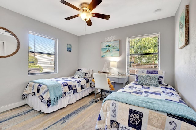 bedroom with multiple windows, wood finished floors, baseboards, and ceiling fan