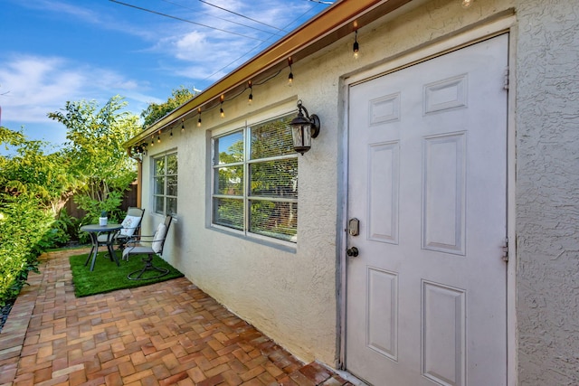 view of exterior entry with a patio area and stucco siding