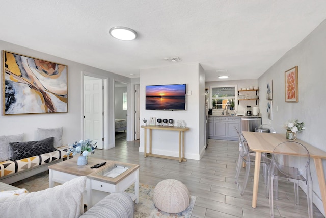 living area featuring visible vents, a textured ceiling, baseboards, and wood tiled floor