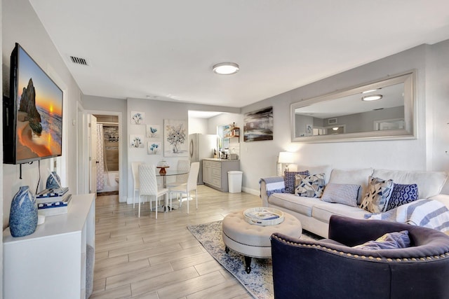 living area with visible vents, light wood-type flooring, and baseboards