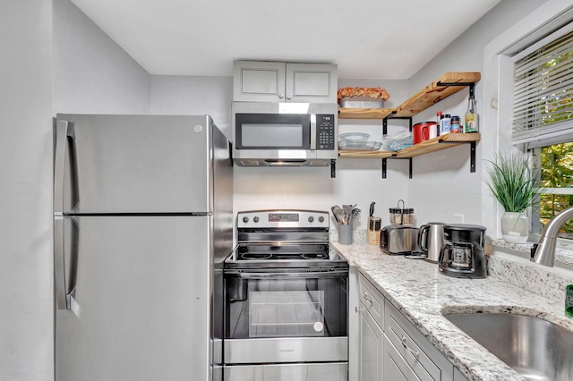 kitchen featuring a sink, light stone counters, and appliances with stainless steel finishes