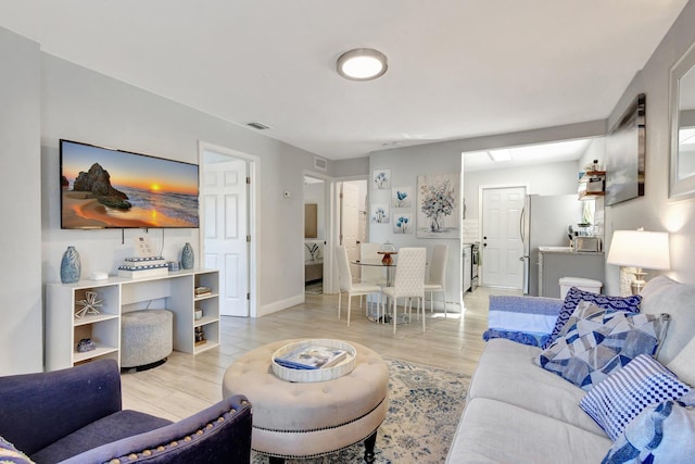 living room featuring visible vents, light wood-type flooring, and baseboards