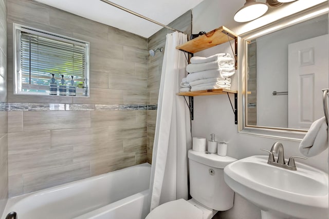 bathroom featuring toilet, shower / bathtub combination with curtain, and a sink