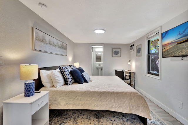 bedroom featuring connected bathroom, baseboards, and light wood-style flooring