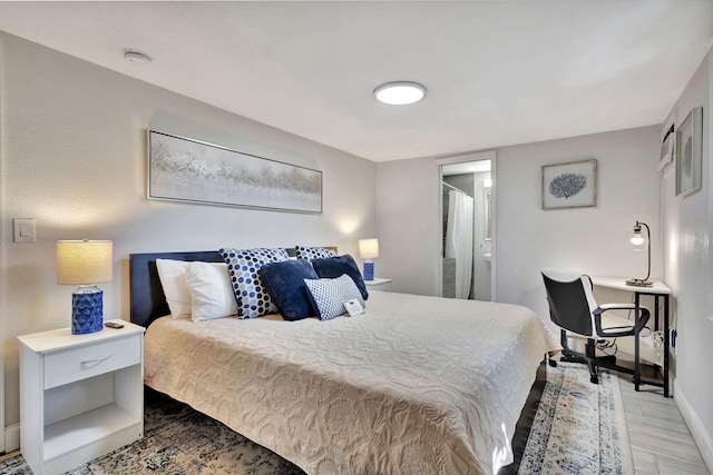 bedroom featuring ensuite bath, baseboards, and wood finished floors