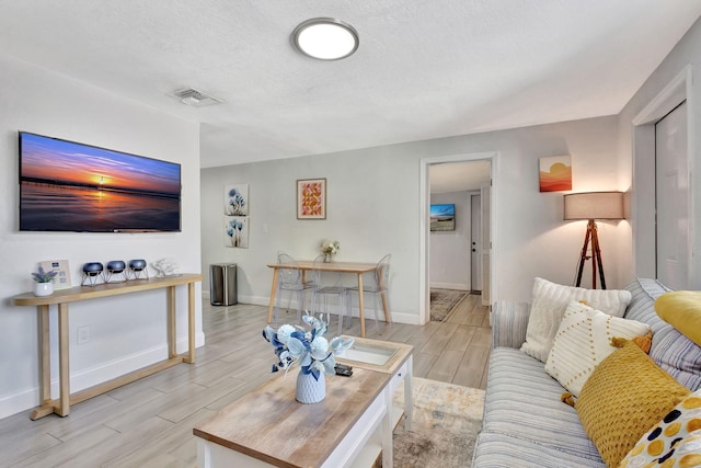 living room featuring visible vents, baseboards, a textured ceiling, and wood tiled floor