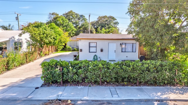 view of front of property with stucco siding, driveway, and fence