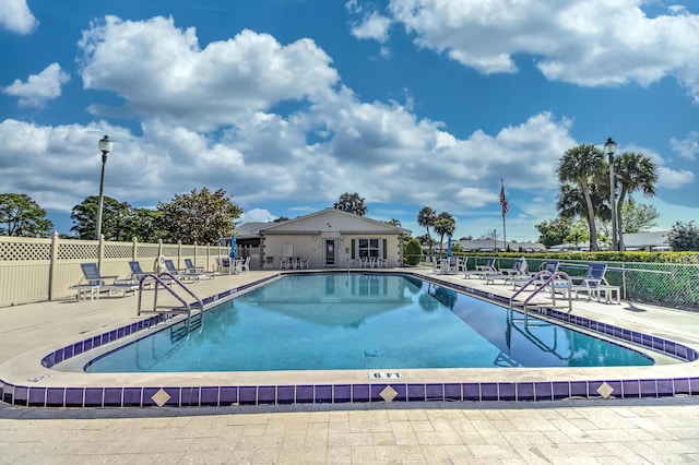 community pool with a patio and fence