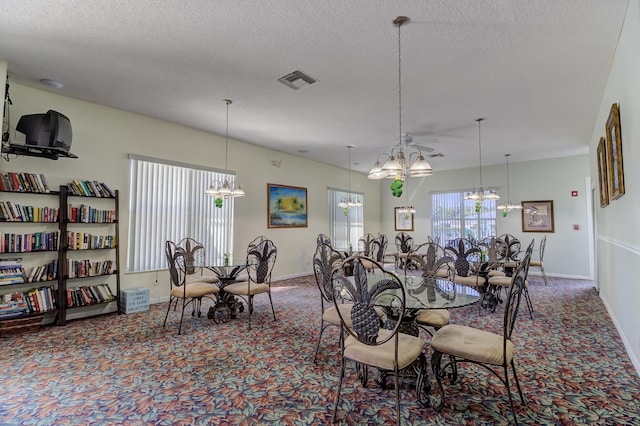 dining space with visible vents, carpet, a chandelier, and a textured ceiling