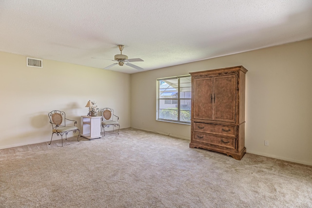 unfurnished room featuring visible vents, light colored carpet, a textured ceiling, and ceiling fan