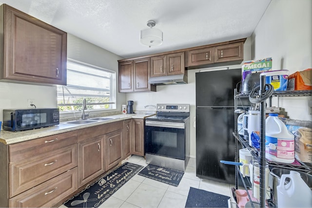 kitchen featuring under cabinet range hood, light countertops, light tile patterned flooring, black appliances, and a sink