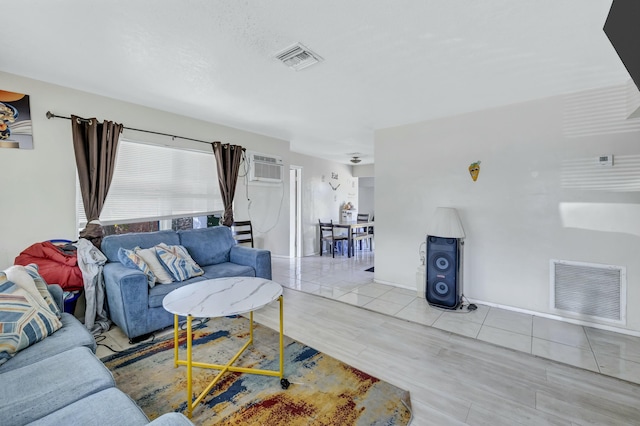 living area featuring a wall mounted air conditioner, visible vents, baseboards, and tile patterned flooring