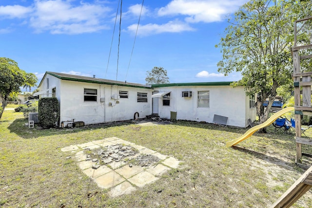 back of house with a yard, stucco siding, and a playground