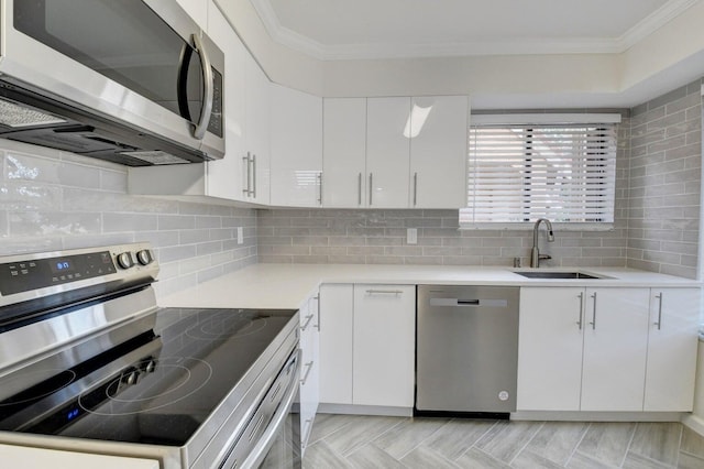 kitchen featuring backsplash, ornamental molding, stainless steel appliances, and a sink