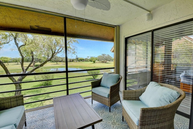 sunroom featuring a ceiling fan and a water view