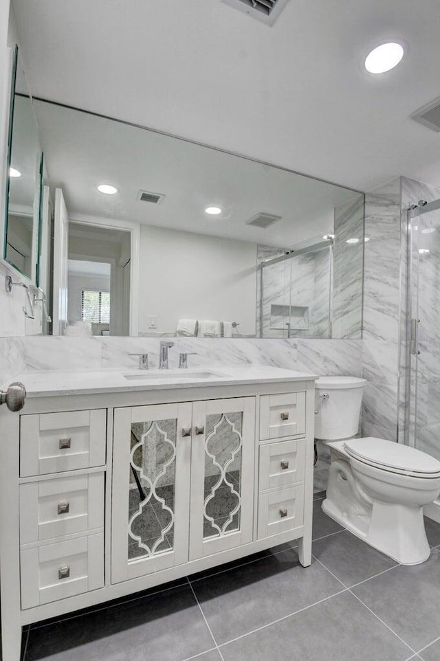 full bath featuring vanity, toilet, visible vents, and a marble finish shower