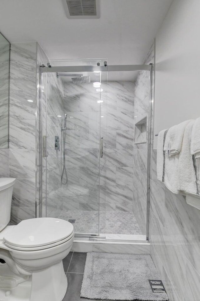 full bath featuring a marble finish shower, visible vents, tile patterned floors, and toilet