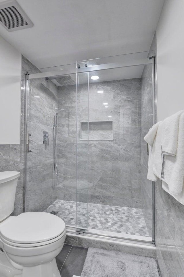 bathroom featuring visible vents, toilet, and a shower stall