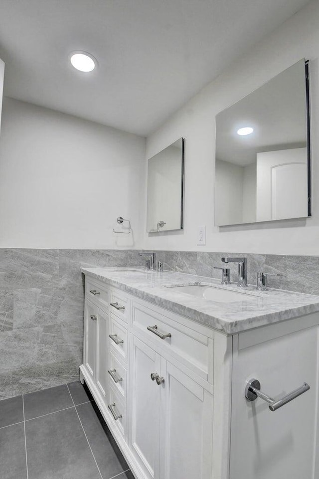 bathroom with tile patterned flooring, double vanity, tile walls, and a sink