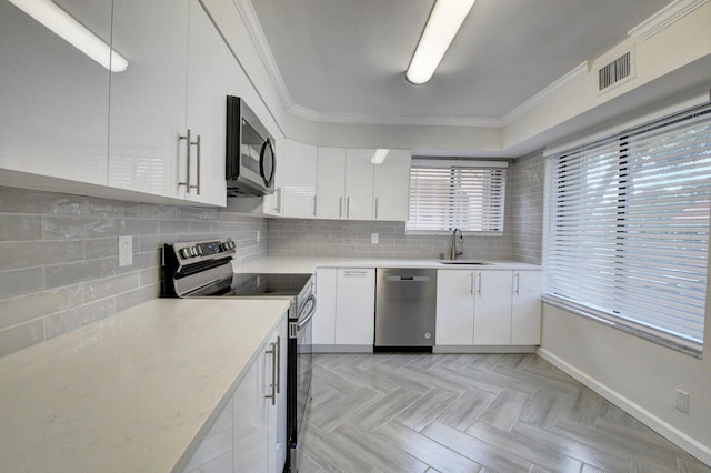 kitchen featuring visible vents, ornamental molding, a sink, stainless steel appliances, and decorative backsplash