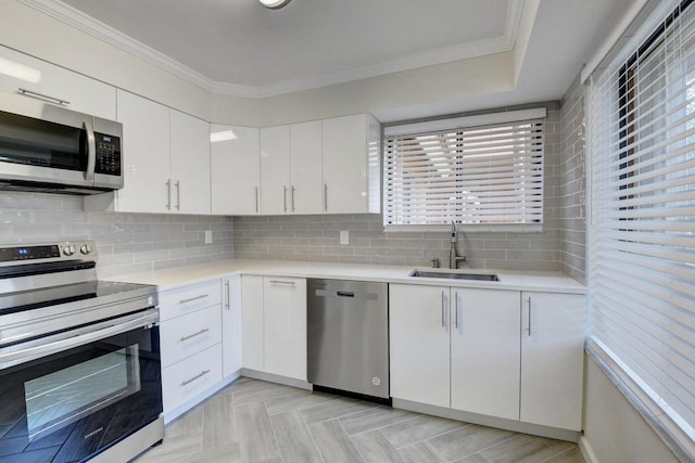 kitchen featuring a sink, stainless steel appliances, crown molding, and light countertops