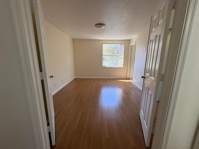 interior space featuring baseboards, a textured ceiling, and wood finished floors