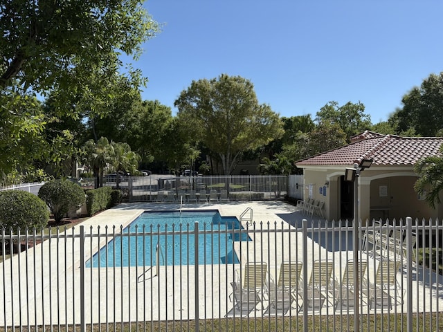 community pool with a patio area and fence