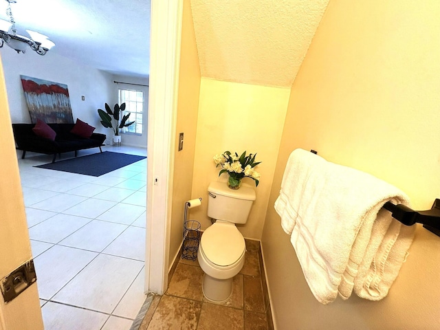 bathroom with baseboards, a textured ceiling, vaulted ceiling, and toilet