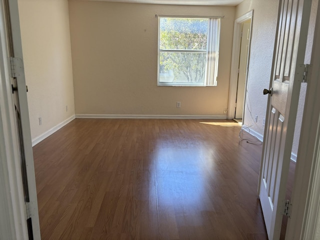 empty room featuring dark wood finished floors and baseboards