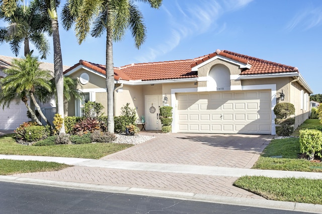 mediterranean / spanish-style home featuring stucco siding, an attached garage, and a tile roof