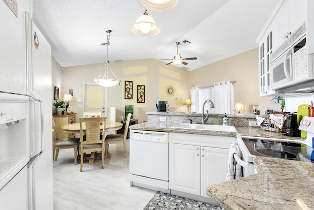 kitchen featuring visible vents, a sink, white appliances, a peninsula, and white cabinets