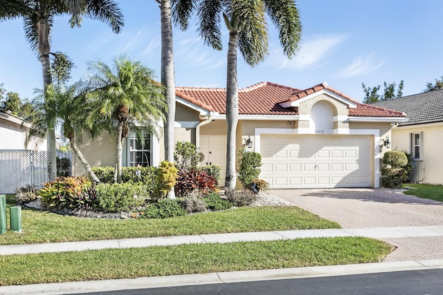 mediterranean / spanish house featuring stucco siding, decorative driveway, a garage, and a tile roof